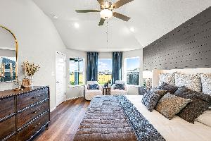 Primary bedroom in the model home located in Carillon at 13305 Eppright Trace Blvd., Manor, TX 